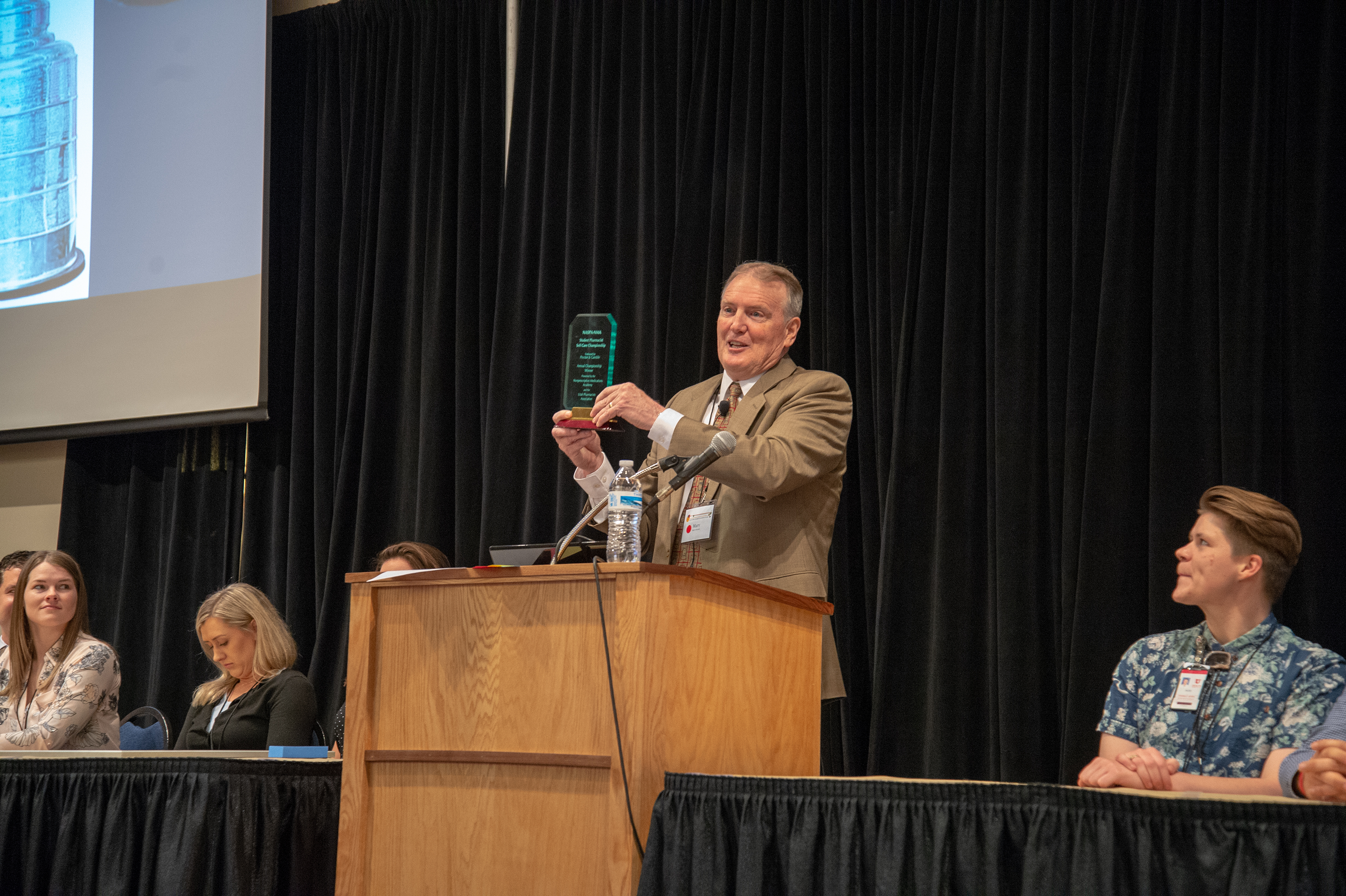 man holding award at podium