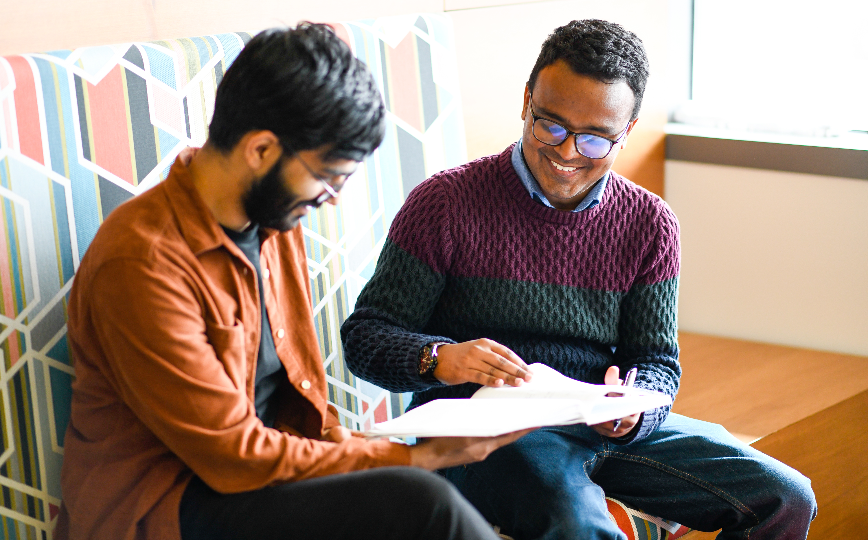 two students sitting and looking at a book