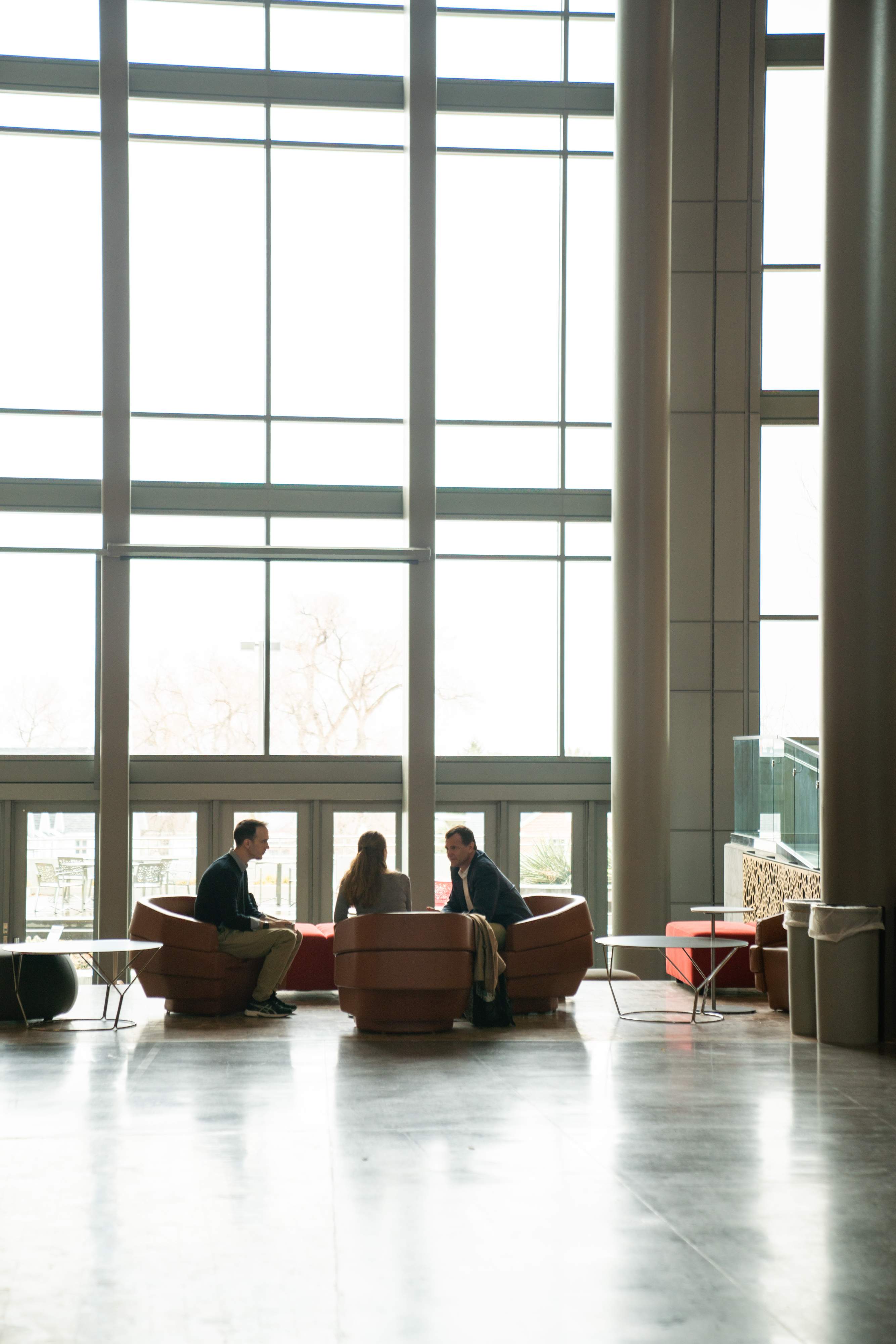 3 individuals sitting, talking in COP atrium