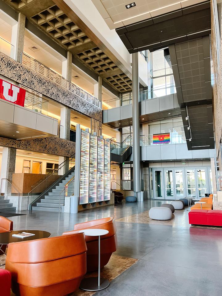a light, airy atrium space in Skaggs Research Building Hall with tables, chairs and University of Utah Flags Hanging