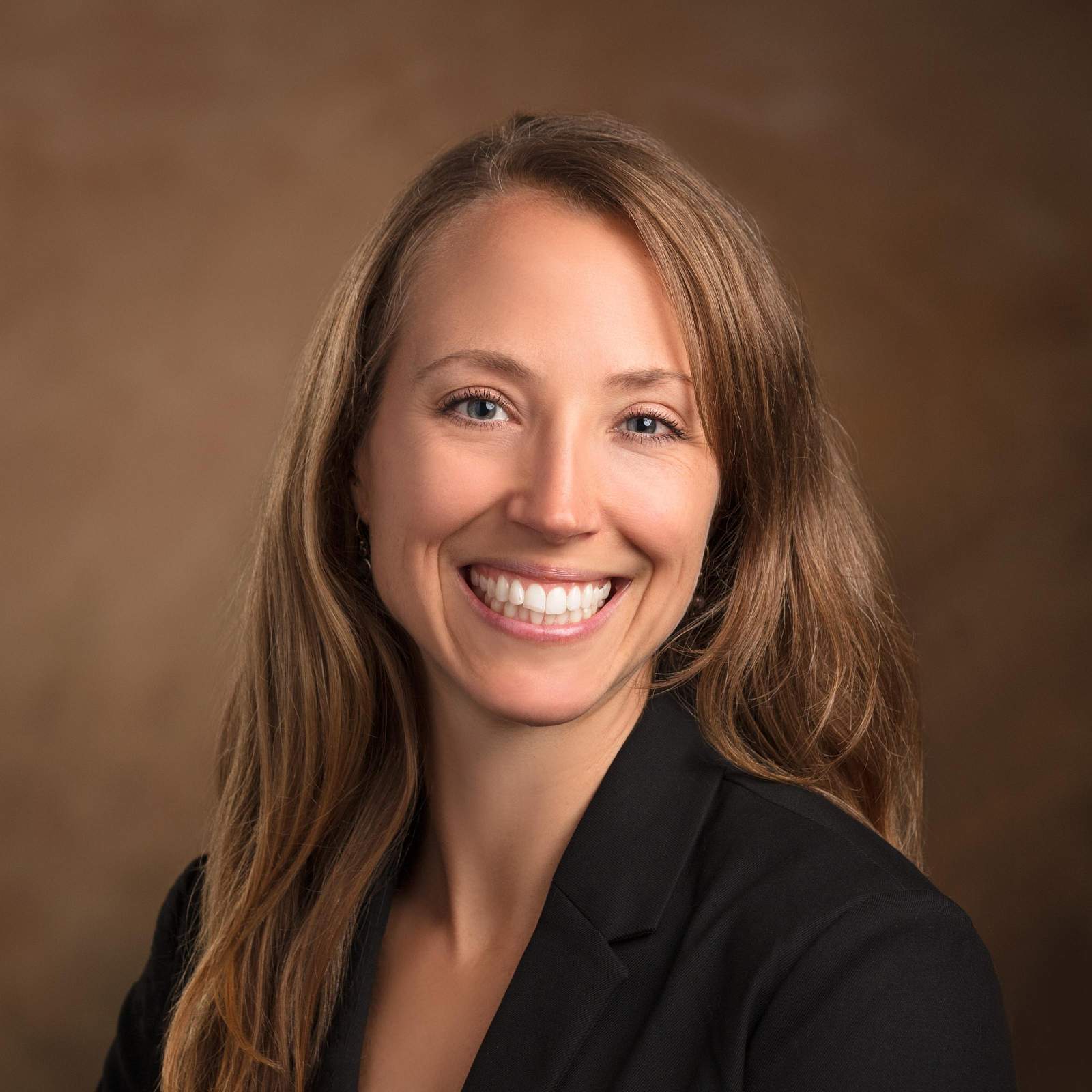 Dr. Abby Pulsipher smiles for headshot in black sports jacket